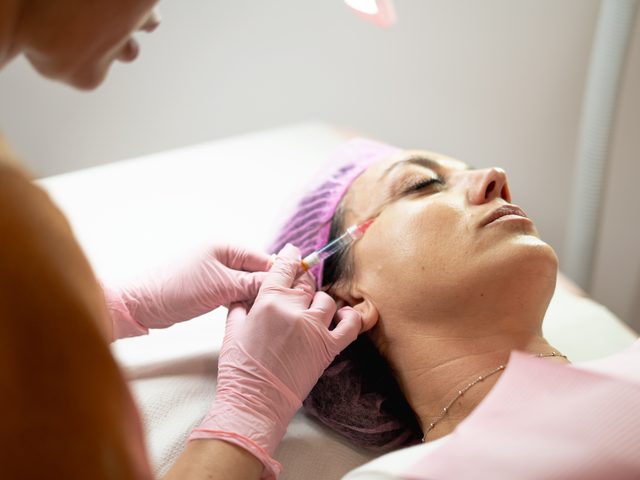 A clinician administering an anti-aging injectable to a patient&rsquo;s face